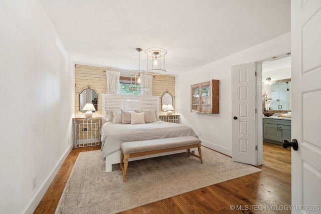 bedroom with wood finished floors, baseboards, and a chandelier