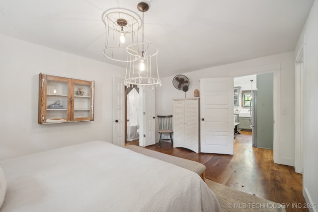 bedroom featuring wood finished floors, a chandelier, and freestanding refrigerator
