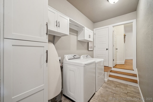 laundry area featuring washer and clothes dryer, cabinet space, and baseboards