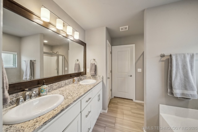 bathroom with a shower stall, baseboards, and double vanity