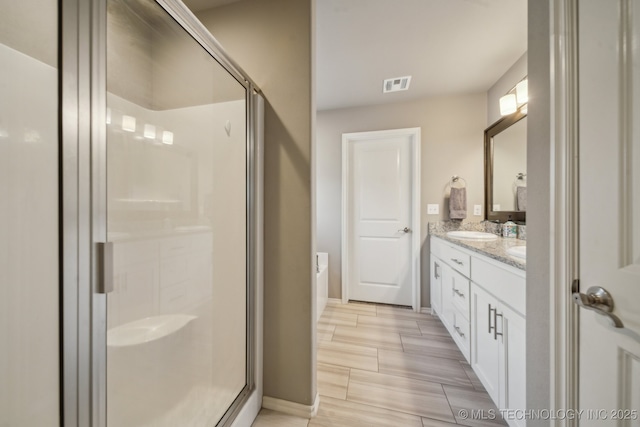 bathroom featuring a shower stall, baseboards, and double vanity