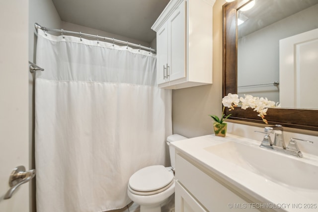bathroom featuring toilet, vanity, and curtained shower