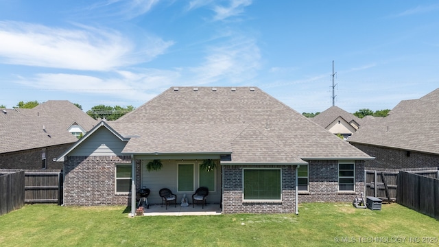 back of house with brick siding, a patio, and roof with shingles