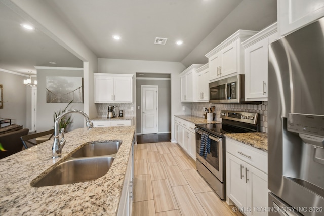 kitchen featuring stainless steel appliances, a sink, backsplash, white cabinets, and recessed lighting