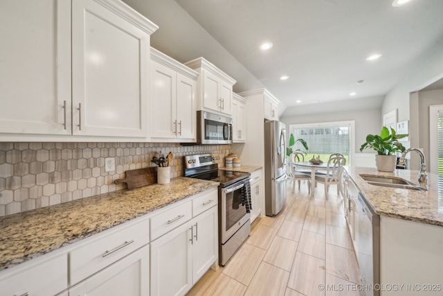 kitchen featuring appliances with stainless steel finishes, a sink, white cabinets, tasteful backsplash, and recessed lighting