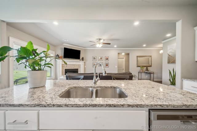 kitchen with a sink, dishwasher, open floor plan, a ceiling fan, and white cabinetry