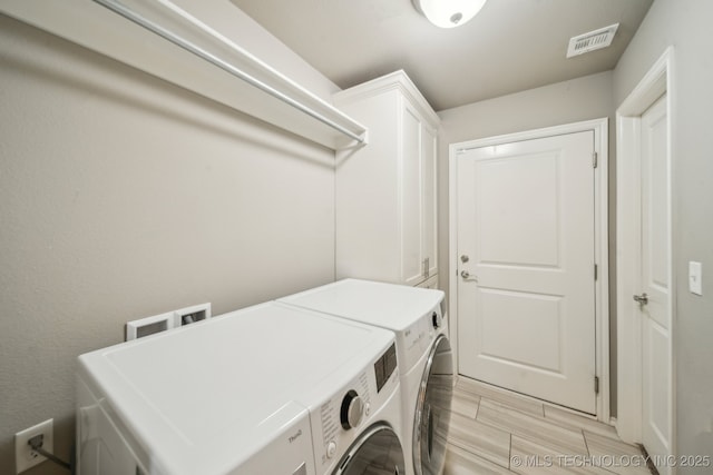 clothes washing area featuring cabinet space and washer and clothes dryer