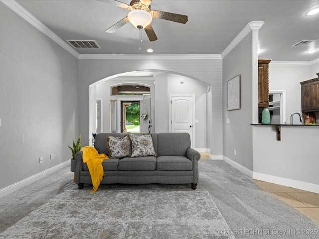 1912 Lester Ave, Bartlesville, OK 74006 - living room featuring arched walkways, light colored carpet, ceiling fan, crown molding, and baseboards