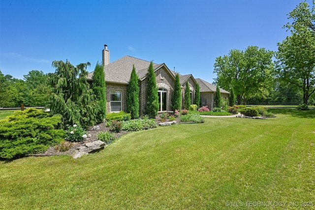 view of front facade featuring a front lawn, a chimney, and brick siding