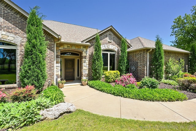 view of front of property with stone siding, brick siding, and roof with shingles
