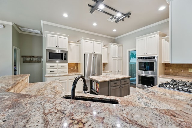 kitchen with appliances with stainless steel finishes, a sink, recessed lighting, crown molding, and light stone counters