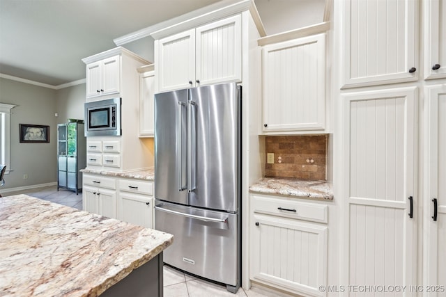 kitchen with appliances with stainless steel finishes, light tile patterned flooring, decorative backsplash, crown molding, and white cabinets