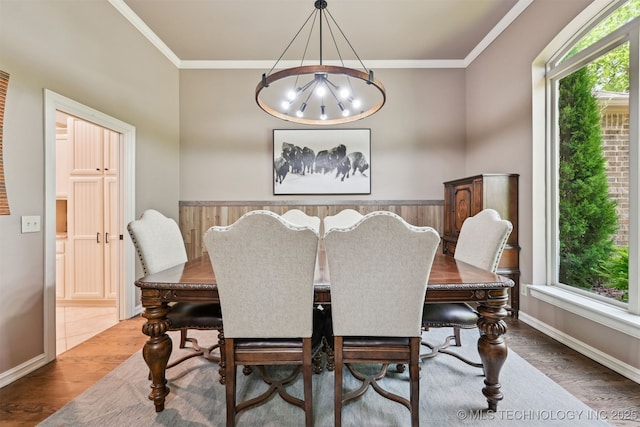 dining room with wood finished floors, healthy amount of natural light, crown molding, and a chandelier