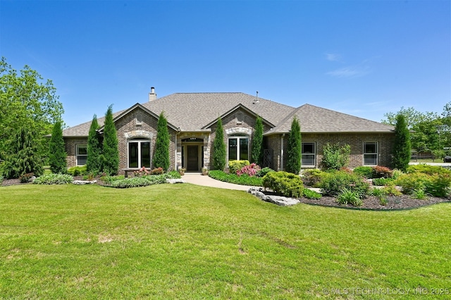 french provincial home featuring brick siding, a front lawn, a chimney, and roof with shingles