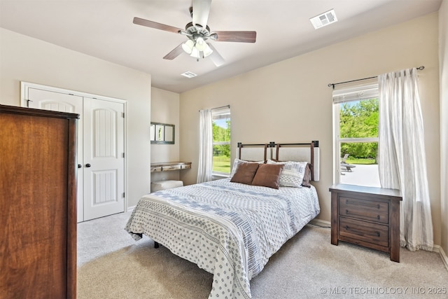 bedroom with light colored carpet, multiple windows, and a closet