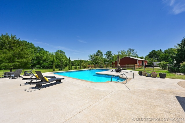 outdoor pool featuring a patio area, fence, and view of scattered trees