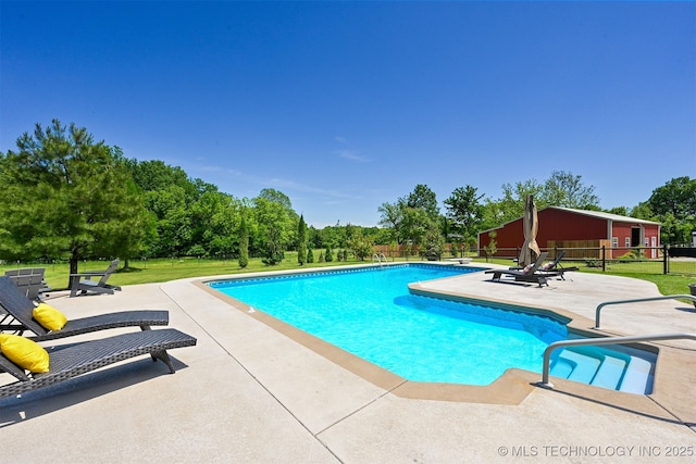 swimming pool with a patio and view of wooded area