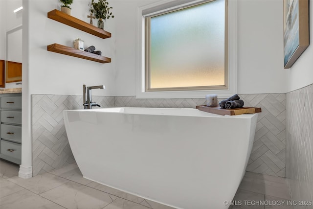 4501 E 108th Pl, Tulsa, OK 74137 - full bathroom with tile walls, marble look tile flooring, wainscoting, and a soaking tub