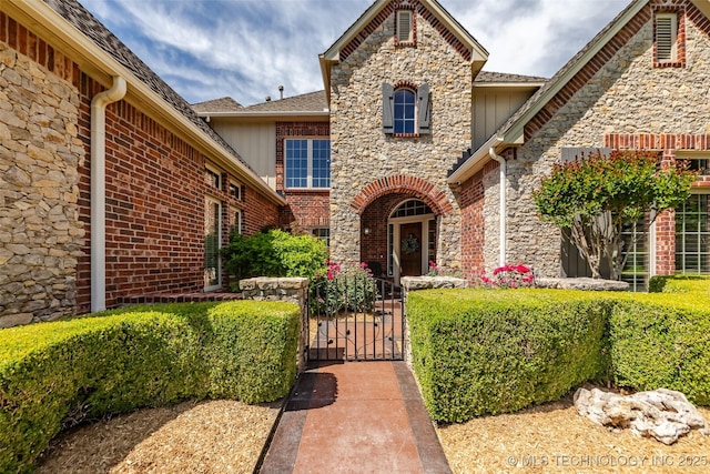 4501 E 108th Pl, Tulsa, OK 74137 - property entrance with stone siding, a gate, fence, and board and batten siding