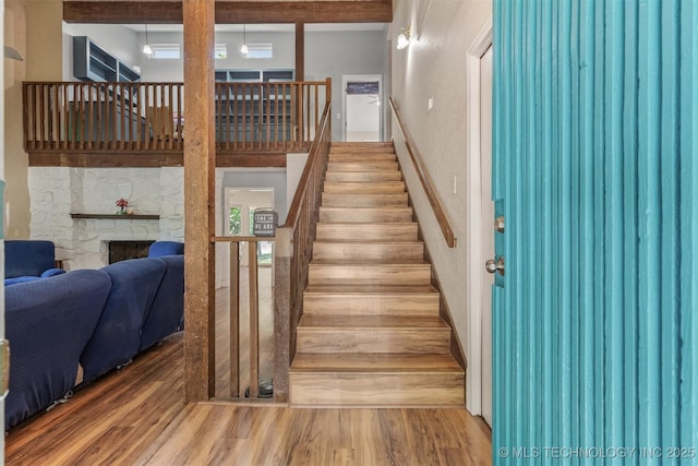 stairs with wood finished floors and a fireplace