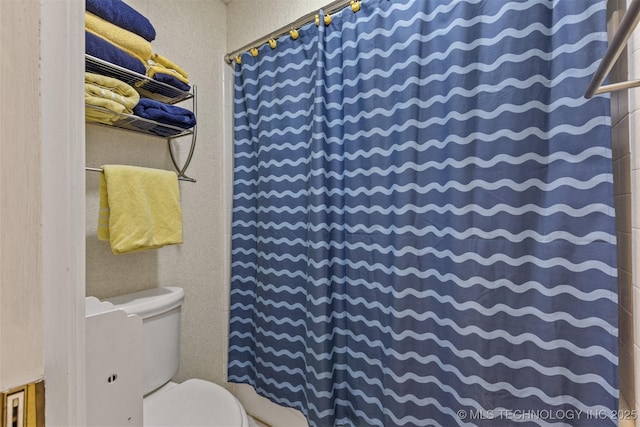 full bath featuring toilet, a textured wall, and curtained shower