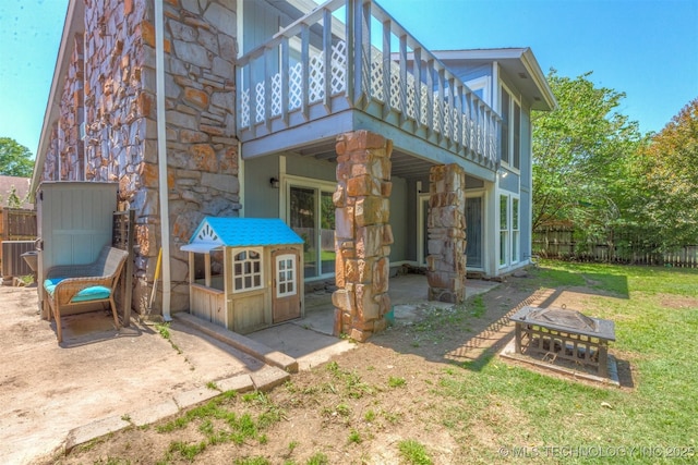 back of property with stone siding and a patio area