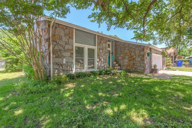 view of front of house featuring stone siding, an attached garage, a front yard, and driveway