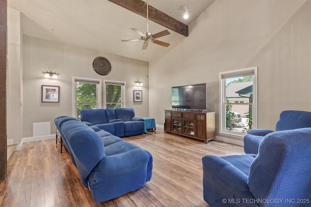 living room with wood finished floors, beamed ceiling, ceiling fan, a high ceiling, and baseboards