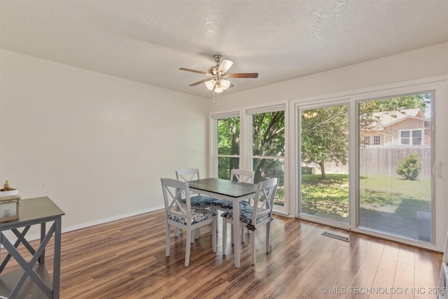 dining space with wood finished floors, baseboards, a ceiling fan, and a textured ceiling
