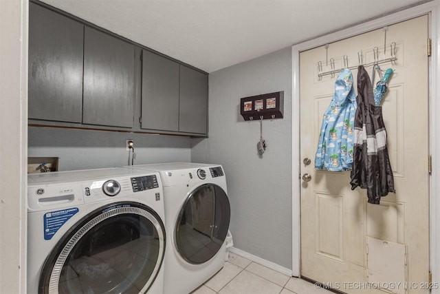 laundry room featuring cabinet space, washer and clothes dryer, light tile patterned floors, and baseboards