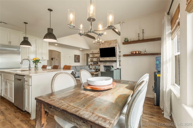 16990 S 33rd W Ave, Glenpool, OK 74033 - dining space featuring dark wood finished floors, a fireplace, vaulted ceiling, and a chandelier