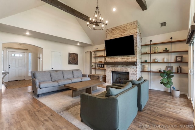 16990 S 33rd W Ave, Glenpool, OK 74033 - living room featuring arched walkways, wood finished floors, a brick fireplace, a chandelier, and high vaulted ceiling