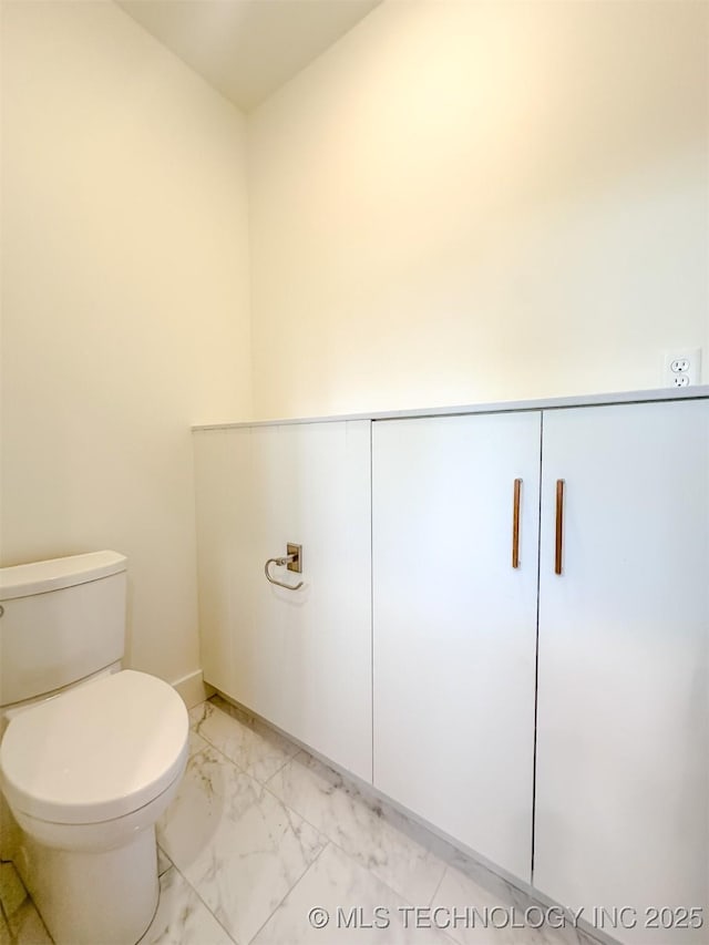 bathroom with marble finish floors, toilet, and baseboards
