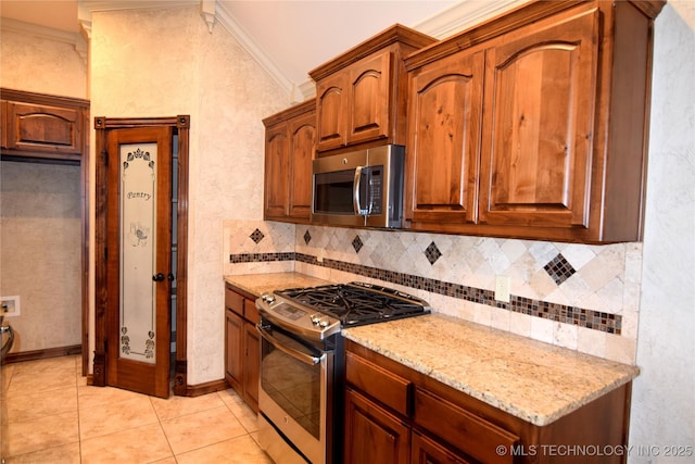 kitchen featuring stainless steel appliances, lofted ceiling, light stone countertops, backsplash, and crown molding