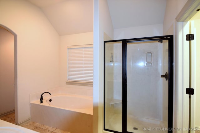 bathroom with a stall shower, a bath, tile patterned flooring, and vaulted ceiling