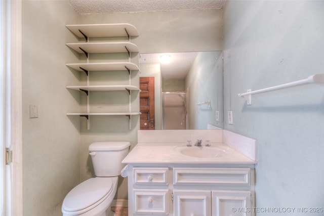 bathroom with toilet, vanity, a textured ceiling, and a shower with shower door