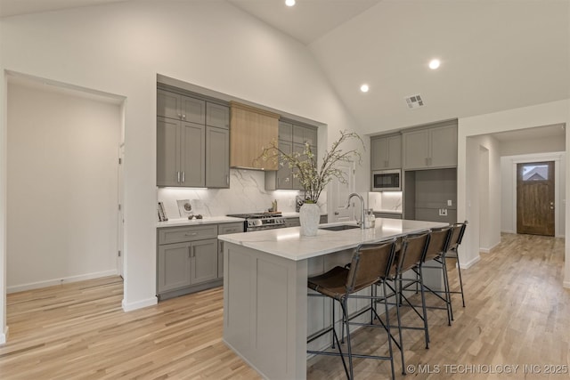 1331 N Beech St, Broken Arrow, OK 74012 - kitchen featuring gray cabinets, a sink, high vaulted ceiling, appliances with stainless steel finishes, and light wood-style flooring