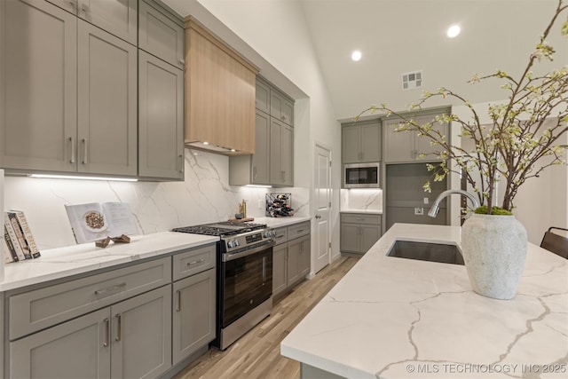 1331 N Beech St, Broken Arrow, OK 74012 - kitchen with stainless steel gas stove, a sink, gray cabinetry, built in microwave, and decorative backsplash