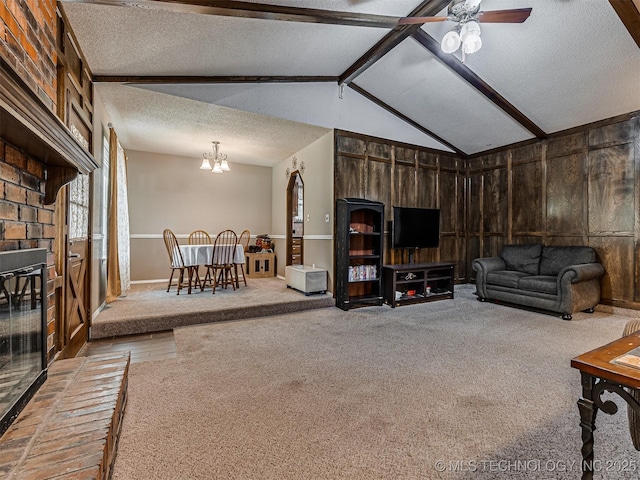 living room with a textured ceiling, carpet floors, ceiling fan, wooden walls, and a chandelier
