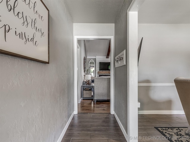 hall featuring dark wood-type flooring and baseboards