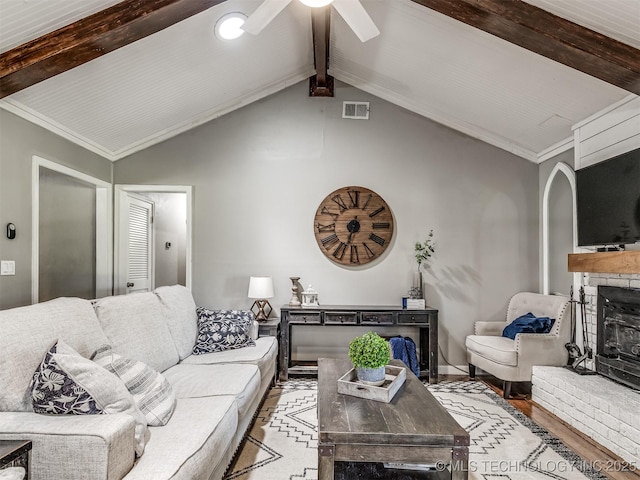 living area with a fireplace, a ceiling fan, arched walkways, and wood finished floors