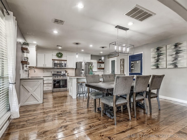 dining room featuring dark wood-type flooring, recessed lighting, baseboards, and arched walkways