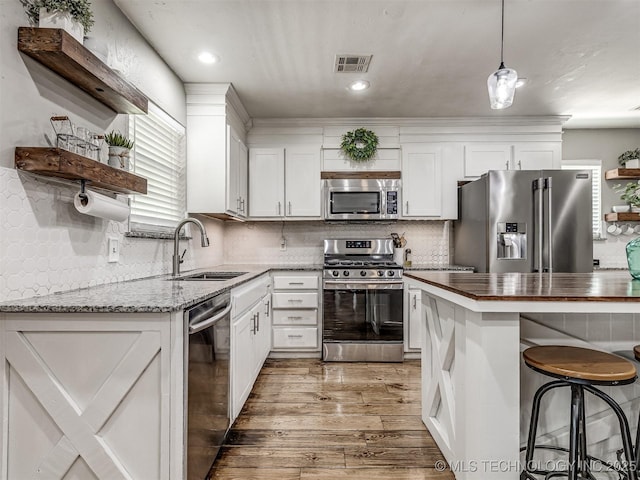 kitchen featuring open shelves, stainless steel appliances, a sink, light wood-style flooring, and wood counters