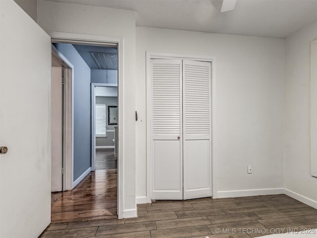 unfurnished bedroom with wood finished floors, a closet, baseboards, and ceiling fan