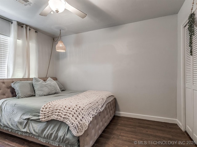 bedroom with dark wood-style floors, baseboards, a closet, and a ceiling fan