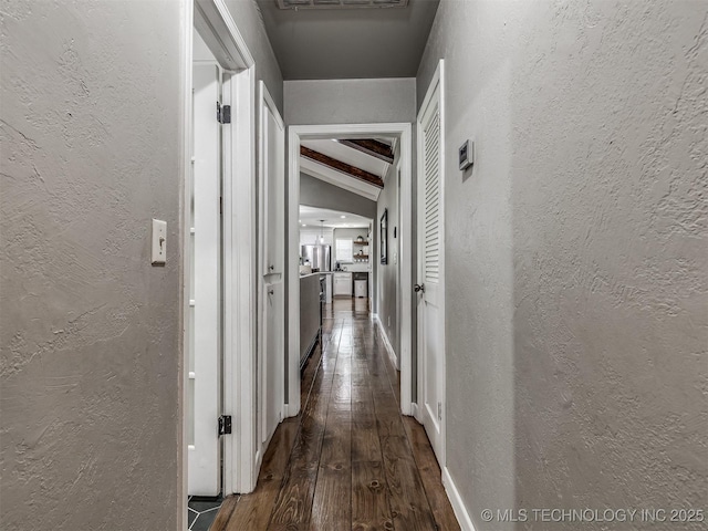corridor with dark wood-style floors and a textured wall