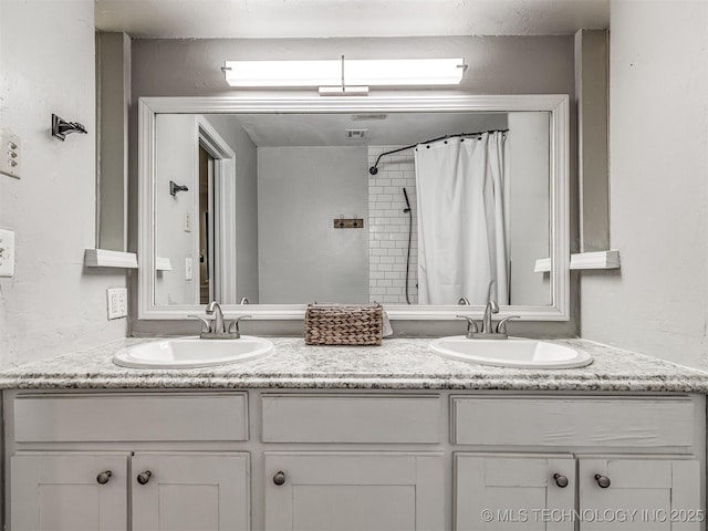 bathroom with double vanity, curtained shower, and a textured wall