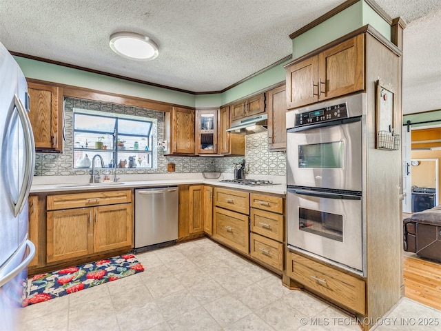 3931 S Oswego Ave, Tulsa, OK 74135 - kitchen featuring appliances with stainless steel finishes, a textured ceiling, a sink, brown cabinetry, and light countertops