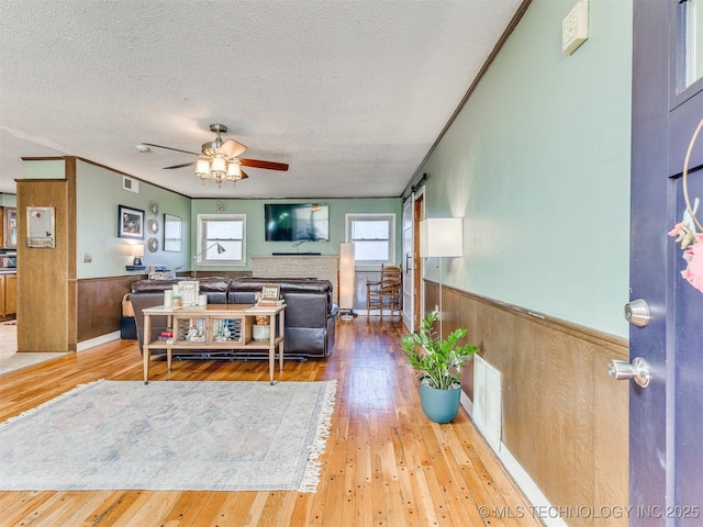 3931 S Oswego Ave, Tulsa, OK 74135 - living room featuring wainscoting, ceiling fan, a textured ceiling, wood-type flooring, and wood walls