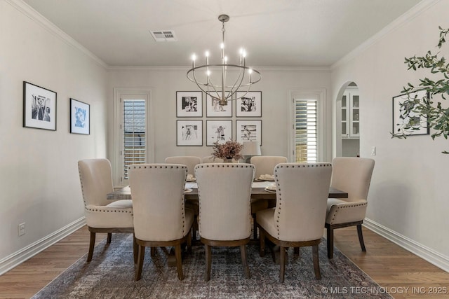9475 E 107th Pl S, Bixby, OK 74133 - dining space with a chandelier, wood finished floors, arched walkways, baseboards, and ornamental molding